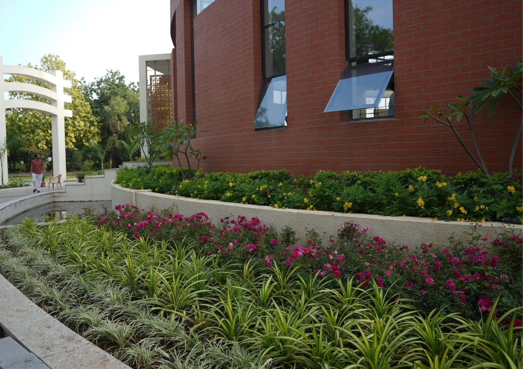 Curved flower beds along the brick wall of the Prerna Sthal dome
